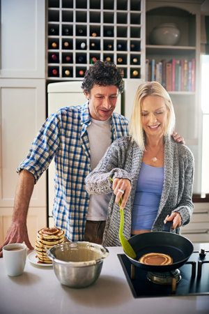 Cooking is love made visible. a happy couple making breakfast together at home.の写真素材