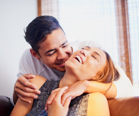 She just loves his sense of humor. a laughing young couple sharing a moment together at home.の写真素材