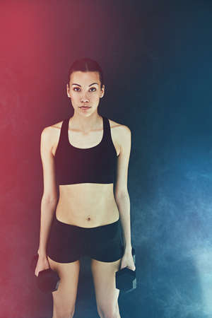 Hard is the only way to train. a young woman working out with dumbbells.の写真素材