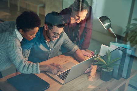 Coming together to get the job done. High angle shot of three young businesspeople looking at a...