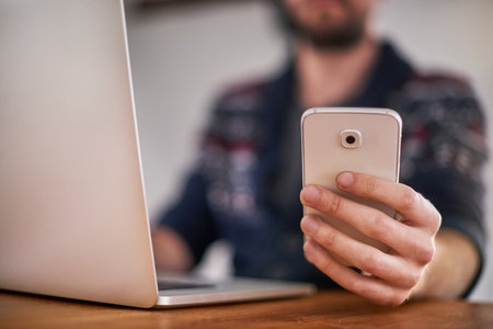 There are endless ways to connect with the world today. Closeup shot of a man using a laptop and cellphone at home.の写真素材