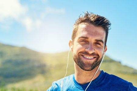 Pump your favourite playlist and get moving. Portrait of a young man listening to music while out...