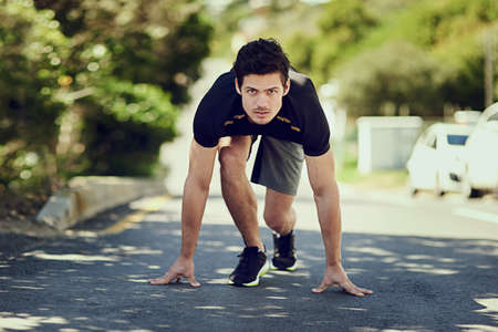 On his mark. Full length portrait of a handsome young man starting his run.の写真素材