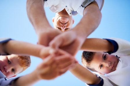 Teamwork makes us all winners. Low angle shot of two young soccerplayers and their coach in a huddle.の写真素材