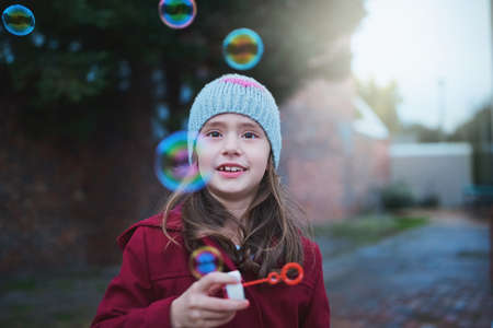 Watch them pop. a little girl blowing bubbles outside.
