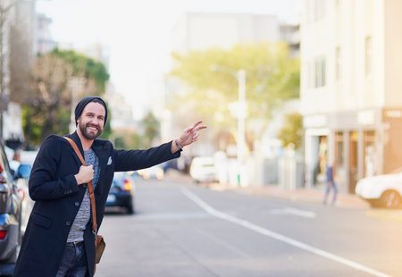 Man on a mission. a young man gesturing to get a cab in the city.の写真素材