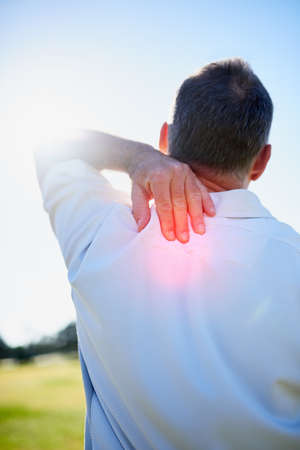 Ouch - feels like Ive pulled that muscle again. Rearview shot of a man rubbing his sore neck while standing outside.の写真素材