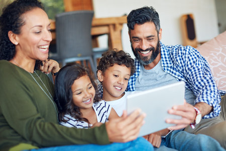 Itll keep them entertained throughout the weekend. a happy family using a digital tablet together at home.の写真素材