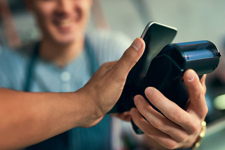 Tap to pay and youre on your way. an unrecognizable barista taking a NFC payment.の写真素材