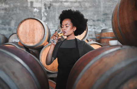 Black winemaker smelling white wine in vineyard cellar, expert analysis by professional, proud female sommelier. Small business owner checking the smell, color and blend of alcohol, enjoying careerの写真素材