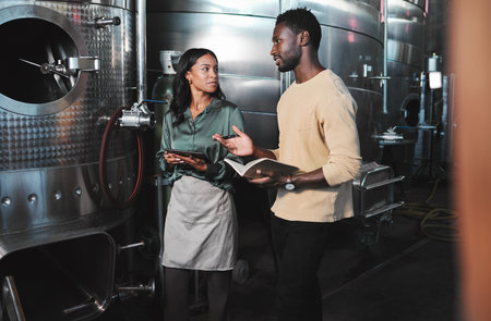 Wine production workers using alcohol machine or distillery equipment in warehouse winery. Business...