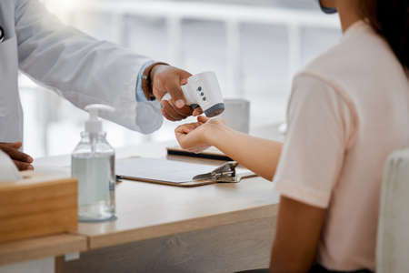 Doctor check covid fever with laser thermometer of sick patient to test for risk of disease or flu...