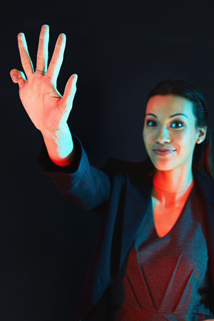How many fingers am I holding up. Portrait of a young businesswoman showing a number with her fingers against a dark background.の写真素材
