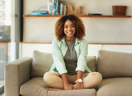 Spending my weekend at home. Full length portrait of an attractive young woman sitting on her sofa at home.の写真素材