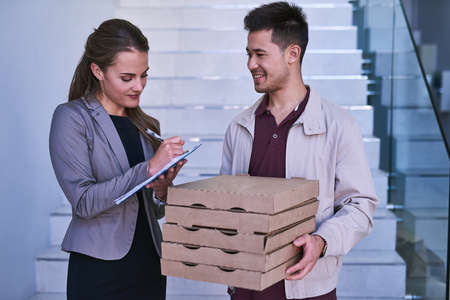 Lunch is delivered. a man making a pizza delivery to a businesswoman at work.の写真素材