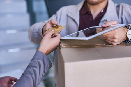 Just another convenient way to pay for your delivery. a courier accepting a credit card payment for a delivery.の写真素材