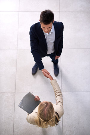 Congratulations, youre hired. High angle shot of two professional businesspeople shaking hands in the office.の写真素材