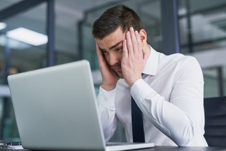 Its been a long day at the office. a stressed out young businessman working on a laptop in an...