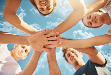 Stronger when we stand together. Low angle shot of a group of young joining their hands together in...
