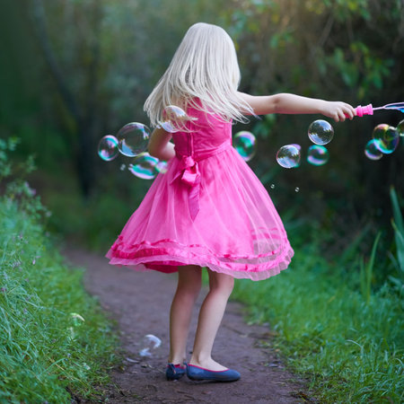 Blown away by all the bubbles. a cute little girl playing outside.の写真素材
