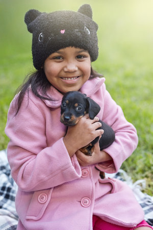 Nothing like puppy love. Cropped portrait of a cute little girl cuddling her puppy while sitting outside.の写真素材