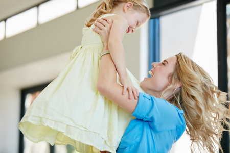 Lifting her up. a young mother playing with her daughter in their home.の写真素材