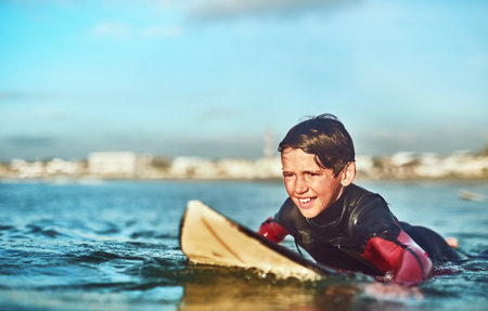 Enjoy life, one wave at a time. a young boy out surfing.の写真素材