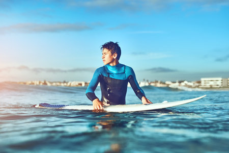 The ocean is educating and lots of fun. a young boy out surfing.の写真素材