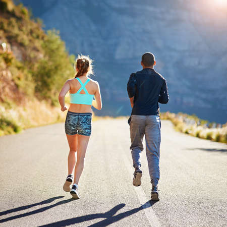Gaining momentum together. Rear view shot of a sporty young couple out for a run together.の写真素材