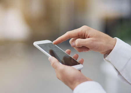 Scrolling through his appointments. an unrecognizable businessman using his cellphone.