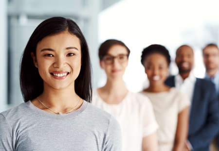 Committed to leading her team to the top. Portrait of a diverse team of professionals standing together in an office.の写真素材