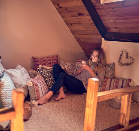 Making time for me. a young woman texting on her smartphone while relaxing in her bedroom at home.の写真素材