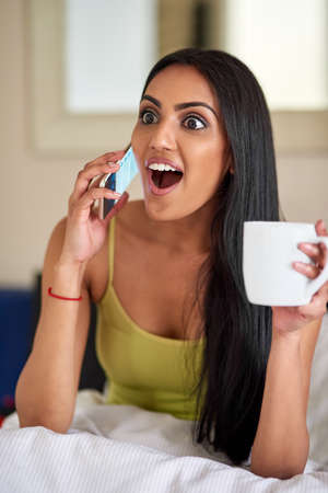 That friend who fills you in on last nights shenanigans. a young woman talking on the phone in bed...