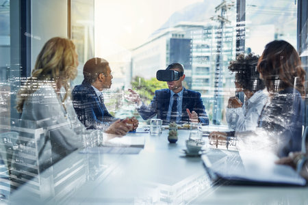 Virtual business meetings. a businessman wearing a VR headset during a meeting in the boardroom.の写真素材