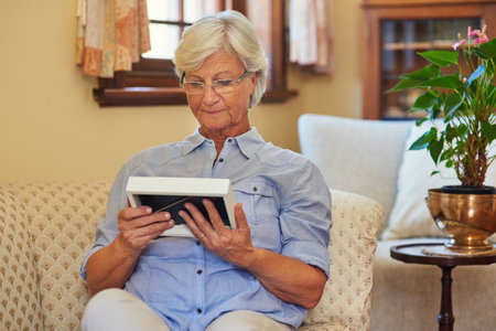 Looking through memories of the past. a senior woman looking at a photo frame at home.