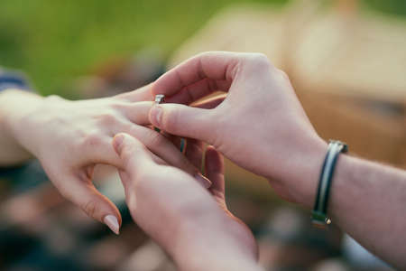 Making a lifelong commitment together. Closeup shot of a man putting an engagement ring onto his fiancees finger.の写真素材