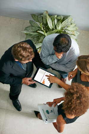 Talking numbers with the team. High angle shot of a group of businesspeople talking together over a...