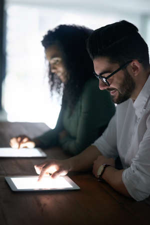 Technology has driven a great amount of change to business. two colleagues working late on their...