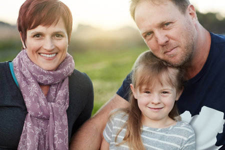 Family is where life begins and love never ends. Portrait of a cute little girl and her parents sitting outside together.の写真素材