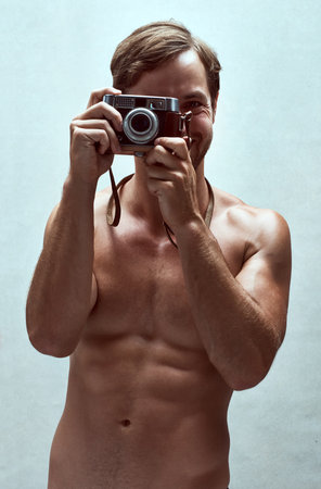 Its hard not to focused on whats behind the camera. a handsome young man posing with a camera.の写真素材