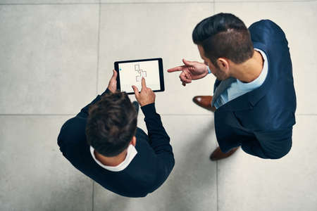 Its the device that helps to expand their ideas. High angle shot of two businessmen working together...