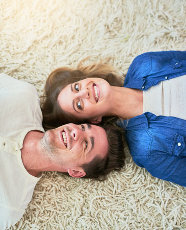 Home is wherever you are. High angle shot of an affectionate young couple lying on their living room...