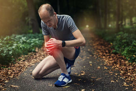 Ouch, that really hurts. a runner experiencing pain from an injured knee while out for a jog.の写真素材