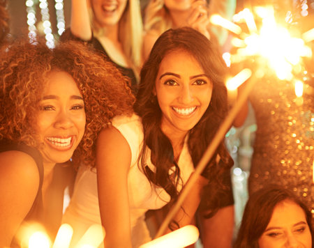Nothing can dull her sparkle tonight. a group of girlfriends having fun with sparklers on a night out.の写真素材