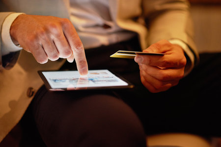 Doing a little shopping after hours. an unrecognizable businessman using his tablet to shop online in the office.の写真素材