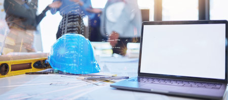 Mockup of architect laptop and planning blueprint, helmet and tools on desk overlay for future architecture building design. Double exposure engineer or construction worker office workplace workspaceの写真素材