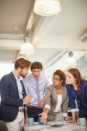 Maximizing project success with teamwork. a group of colleagues going over paperwork during a...