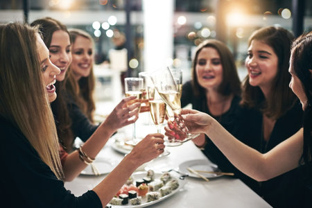 Cheers to friendship. a group of young girlfriends toasting during a dinner party at a restaurant.の写真素材