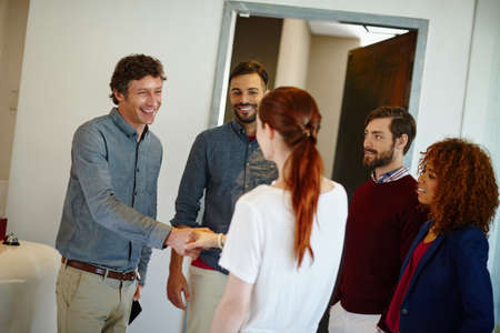 We cant wait to hear your ideas. a young businesswoman being introduced to her new coworkers in the office.の写真素材