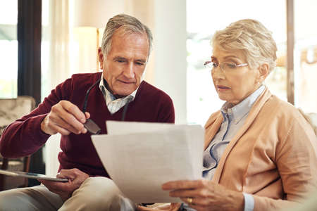 They believe in keeping track of all their expenses. an elderly couple working out a budget while...